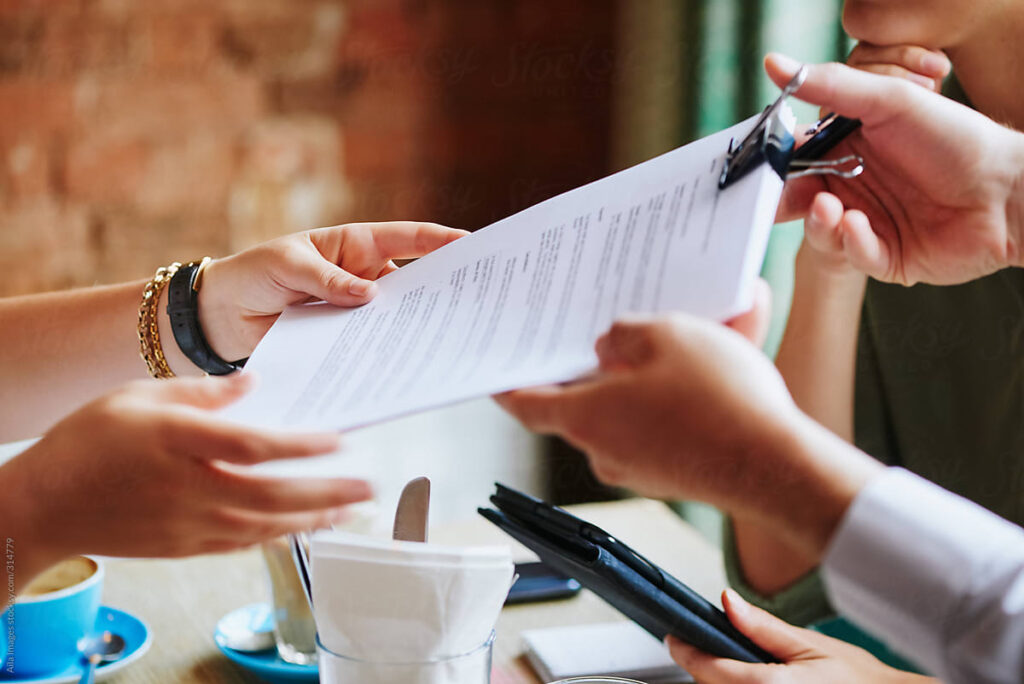 Lawyer Handing Over Legal Document At A Meeting In A Cafe