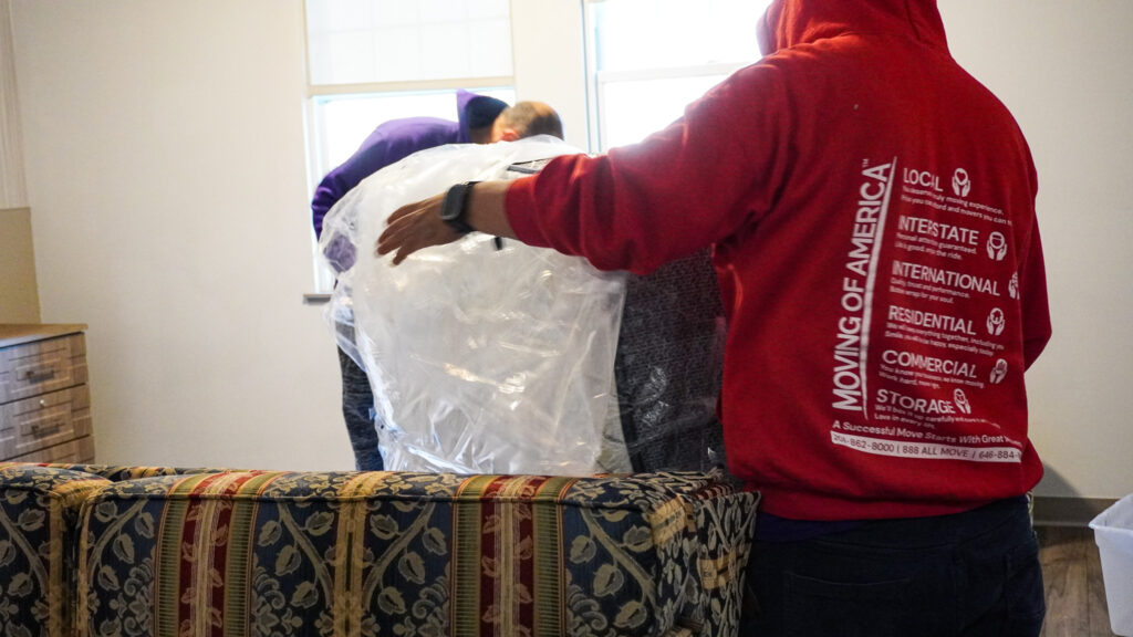Local movers in New Jersey wrapping and protecting furniture with plastic and padding during a residential move.